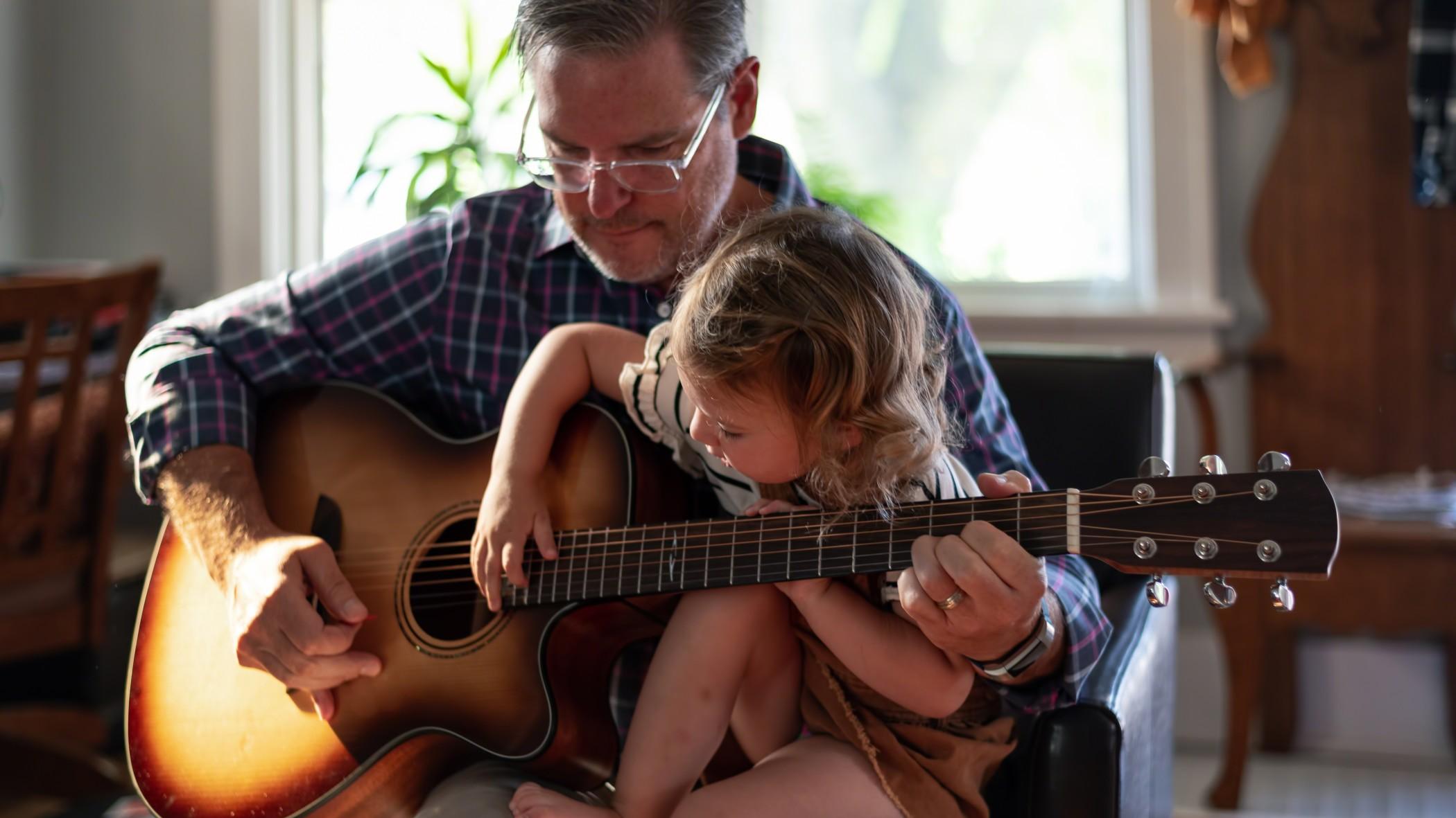 Grandfather playing guitar with granddaughter
