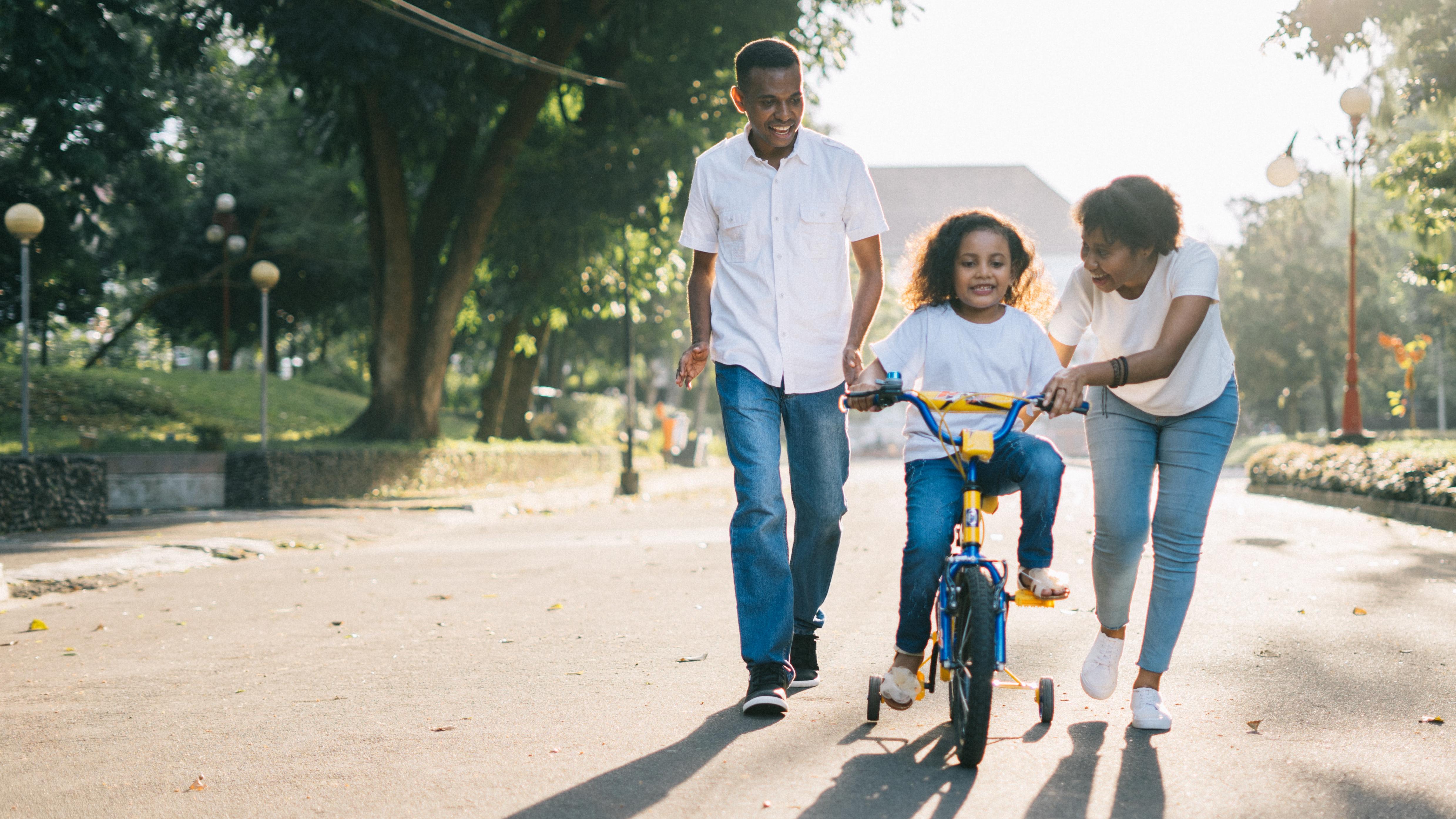 Young Family teaching child how to ride a bike