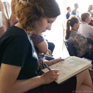 Woman taking notes in a room of people